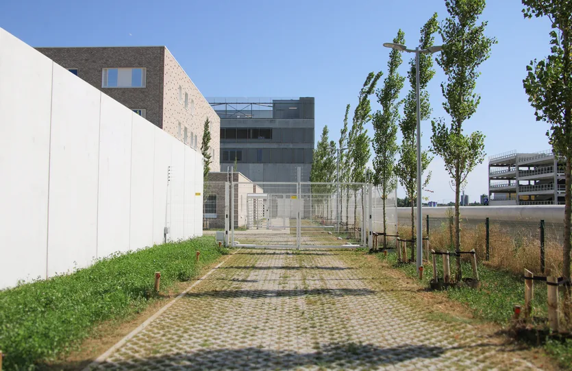 Wandelpad tussen de betonnen muur en de gebouwen van het arresthuis